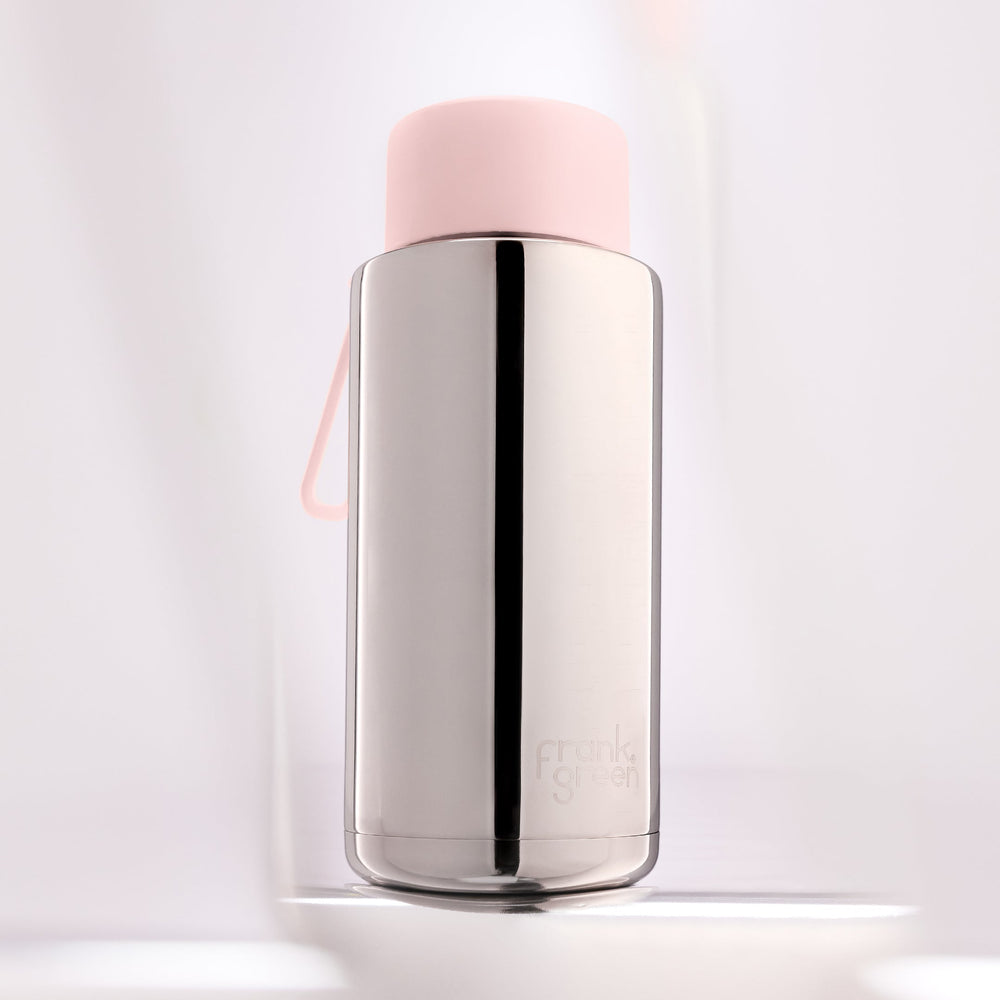 Stainless steel water bottle with a pink cap on a light gray background